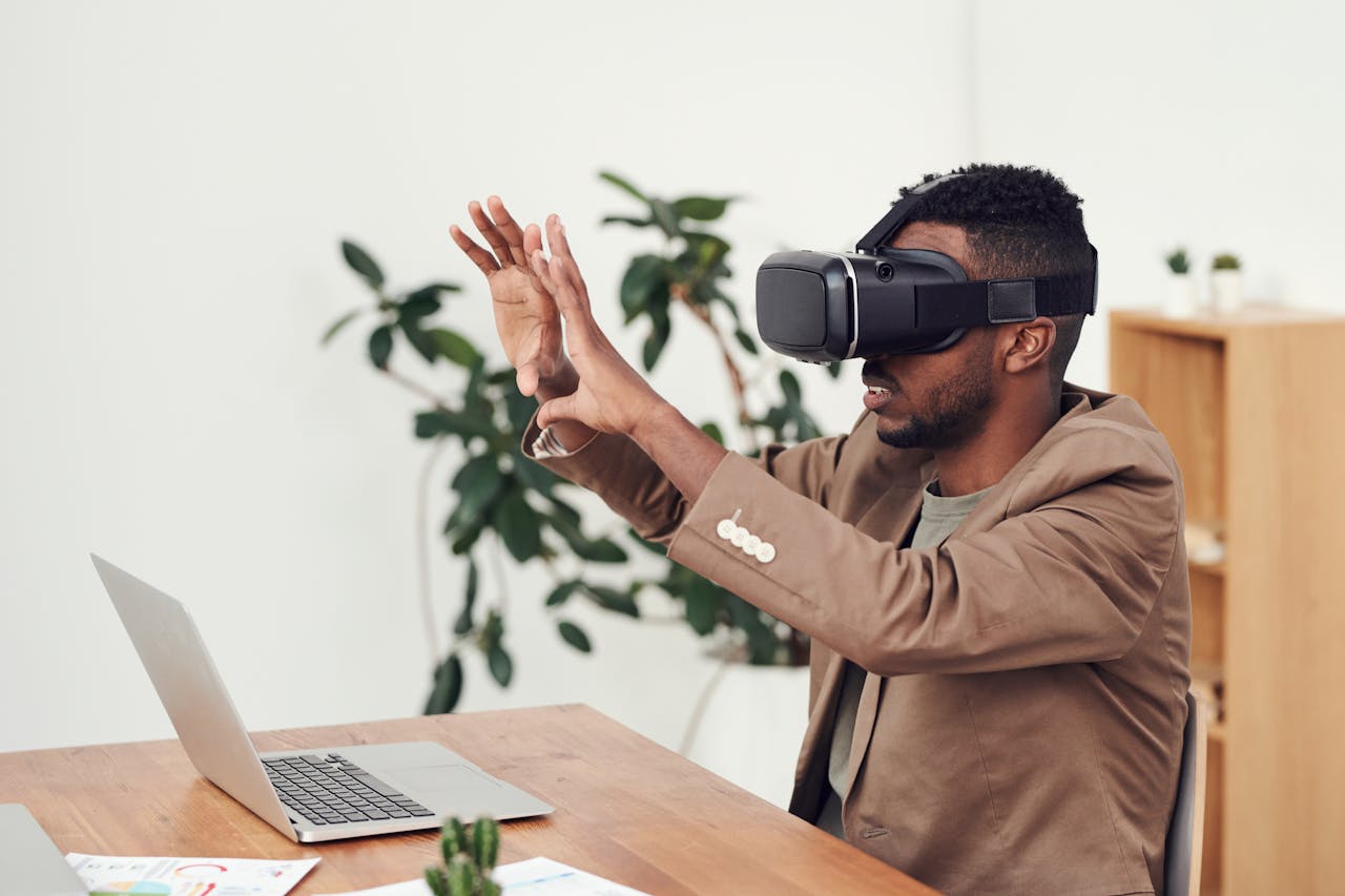 Man using a VR headset in an office with a laptop, engaging with virtual content.